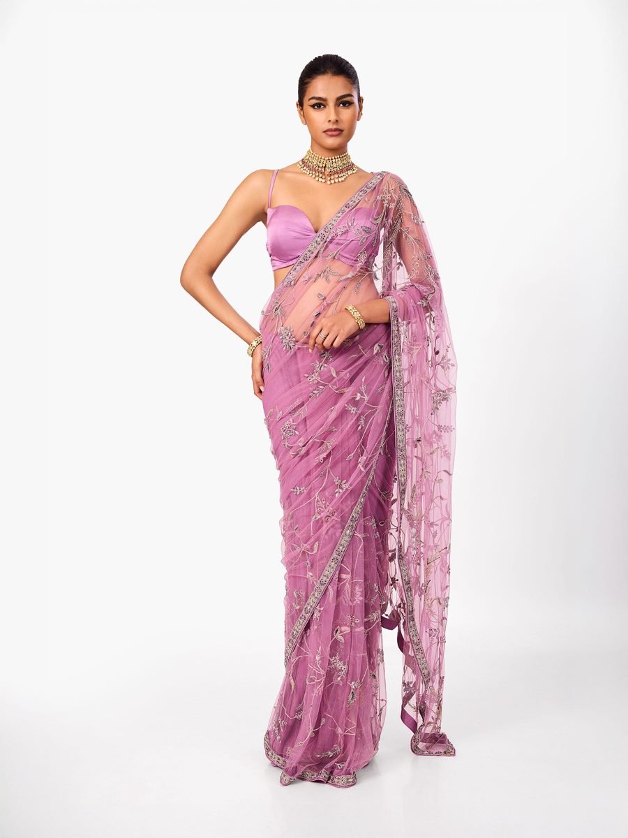 A pink embroidered net saree draped over a lilac blouse