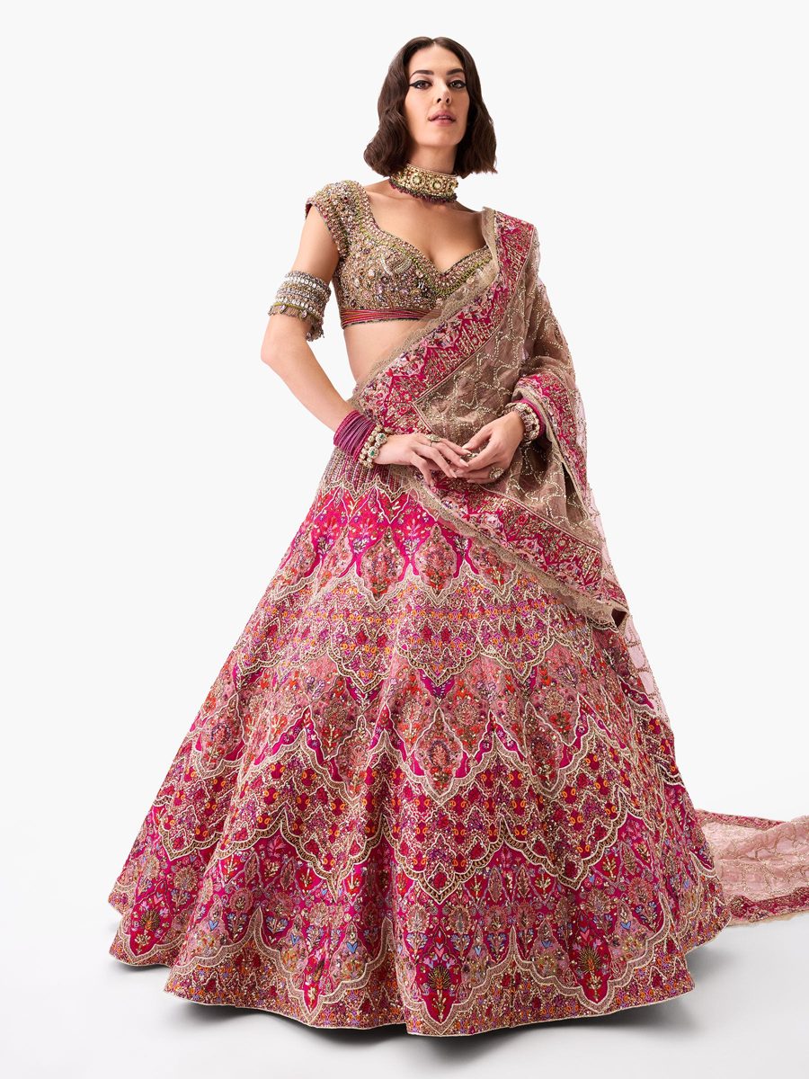 A magenta and gold bridal lehenga with a long train